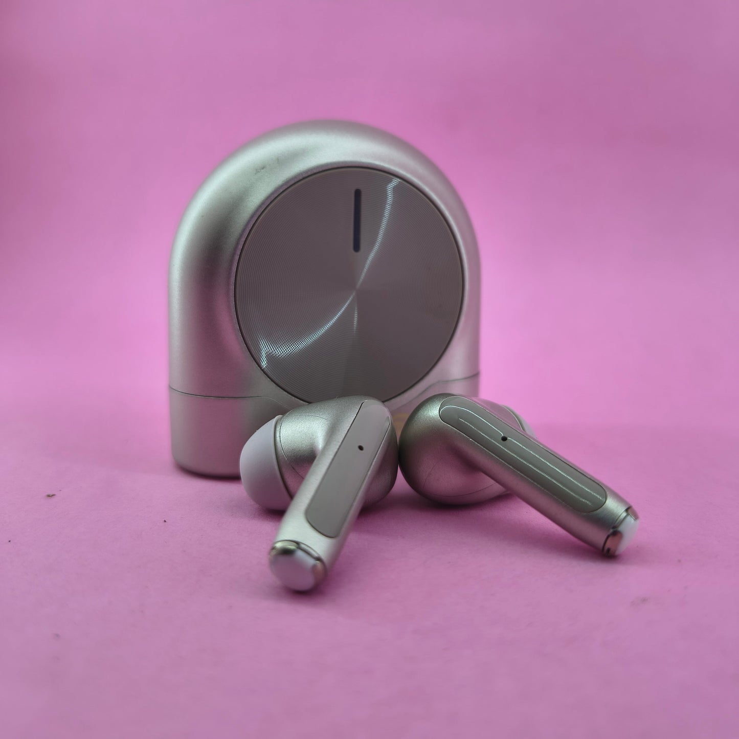 Silver wireless earbuds on a pink background